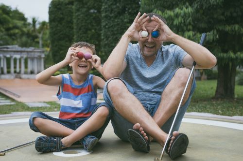 Man and child acting silly with golf balls