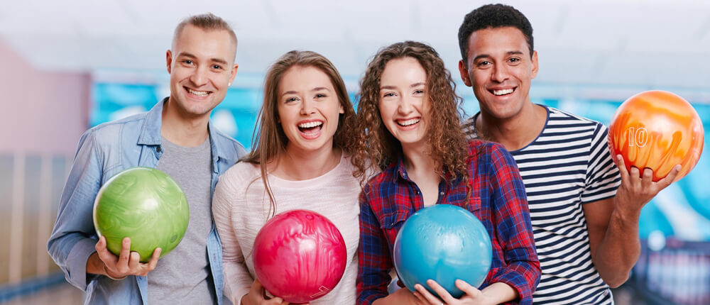 Four young adults posed with bowling balls.